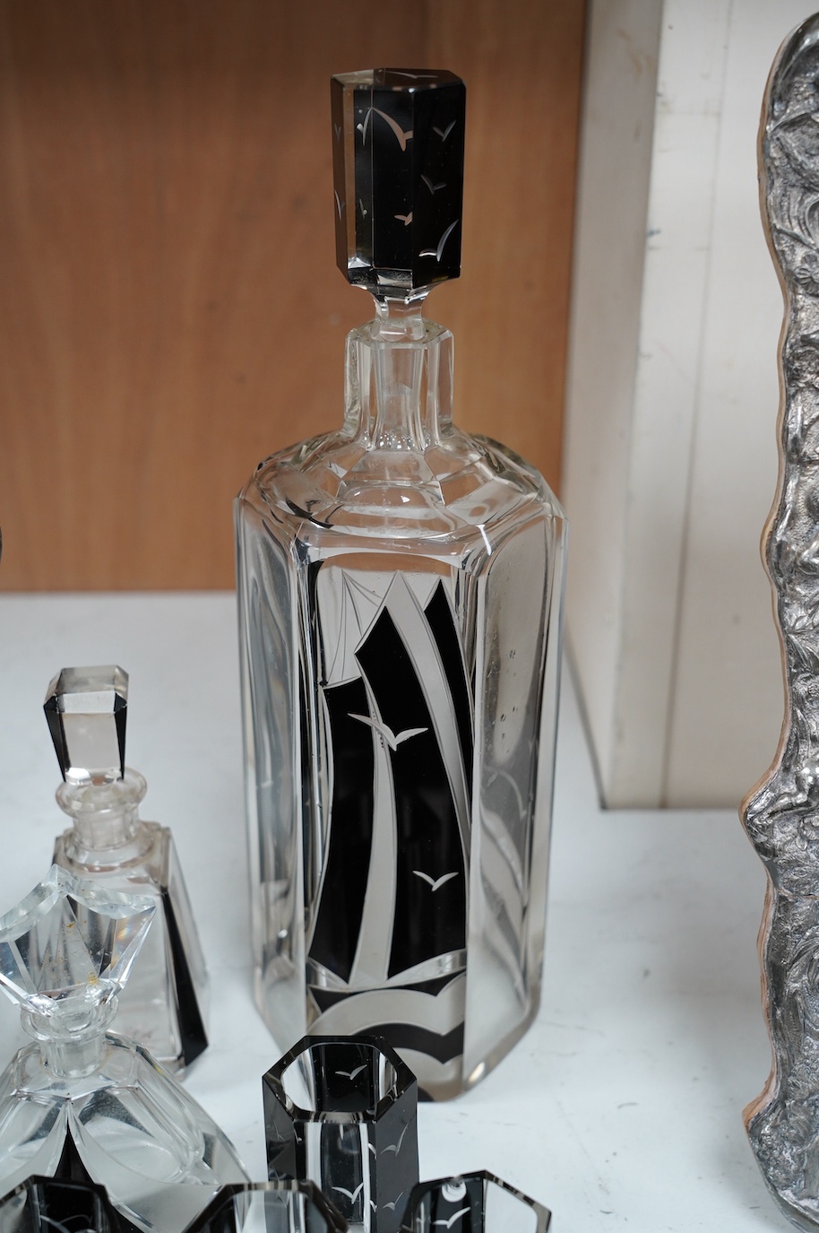 In the manner of Karl Palda (Czechoslovakian), an Art Deco flashed glass liqueur set comprising of a decanter and seven glasses, decorated with gulls and ships, together with a similar vase and two scent bottles and stop